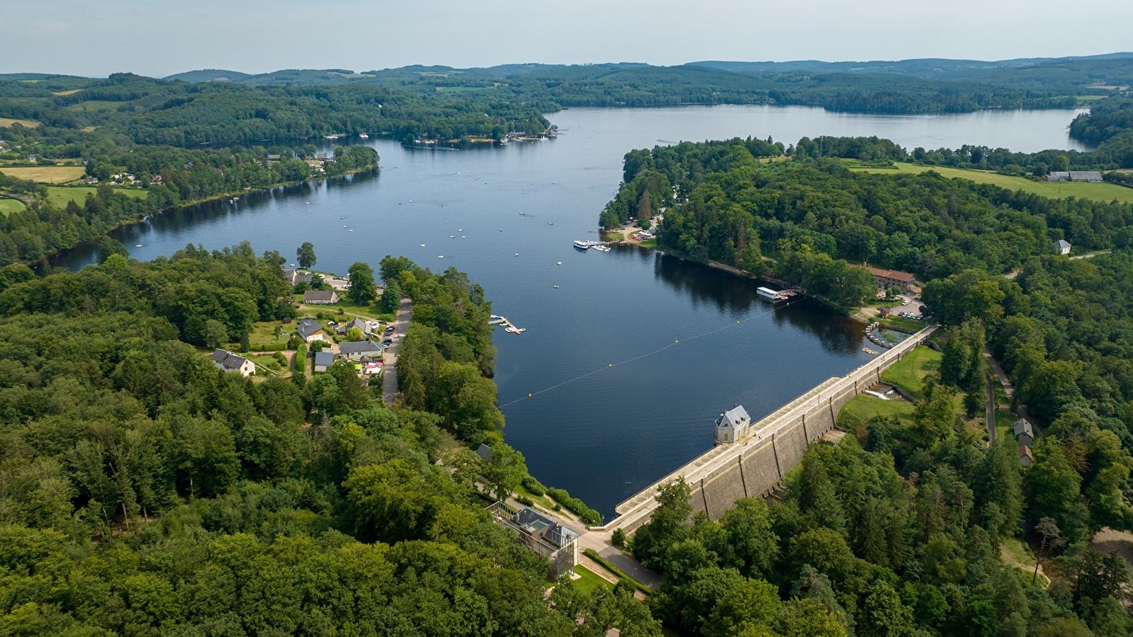 Vue aérienne du lac des Settons et de son barrage, entourés de forêts dans le Morvan.