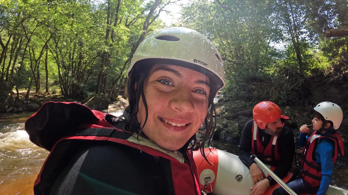 Jeune participante souriante en casque blanc, au premier plan d’un raft sur le Chalaux, dans le Morvan.